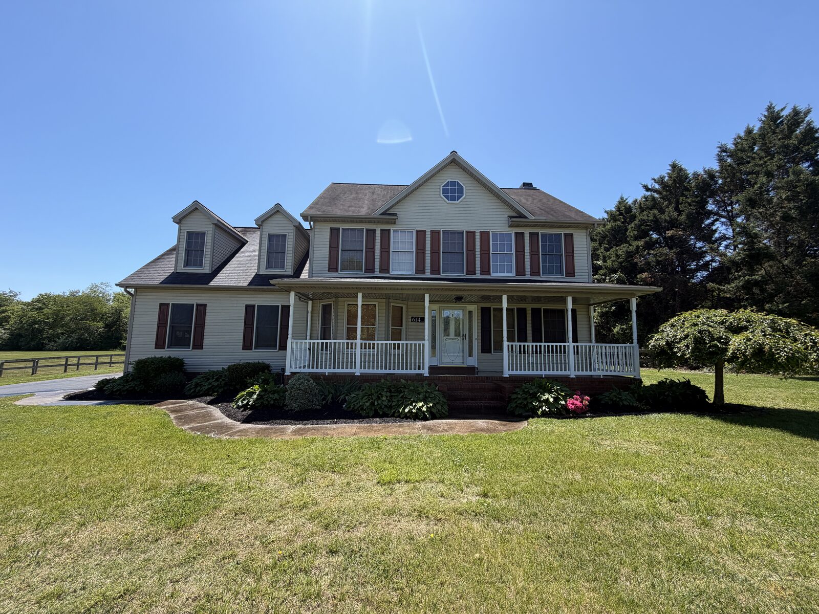 Two-story farmhouse with wrap-around porch after professional house washing in Delaware